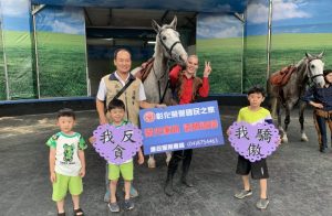 政風室主任劉昌元與學童手持宣導標語與來自斯洛伐尼亞的世界8大名馬「利比扎馬」合影