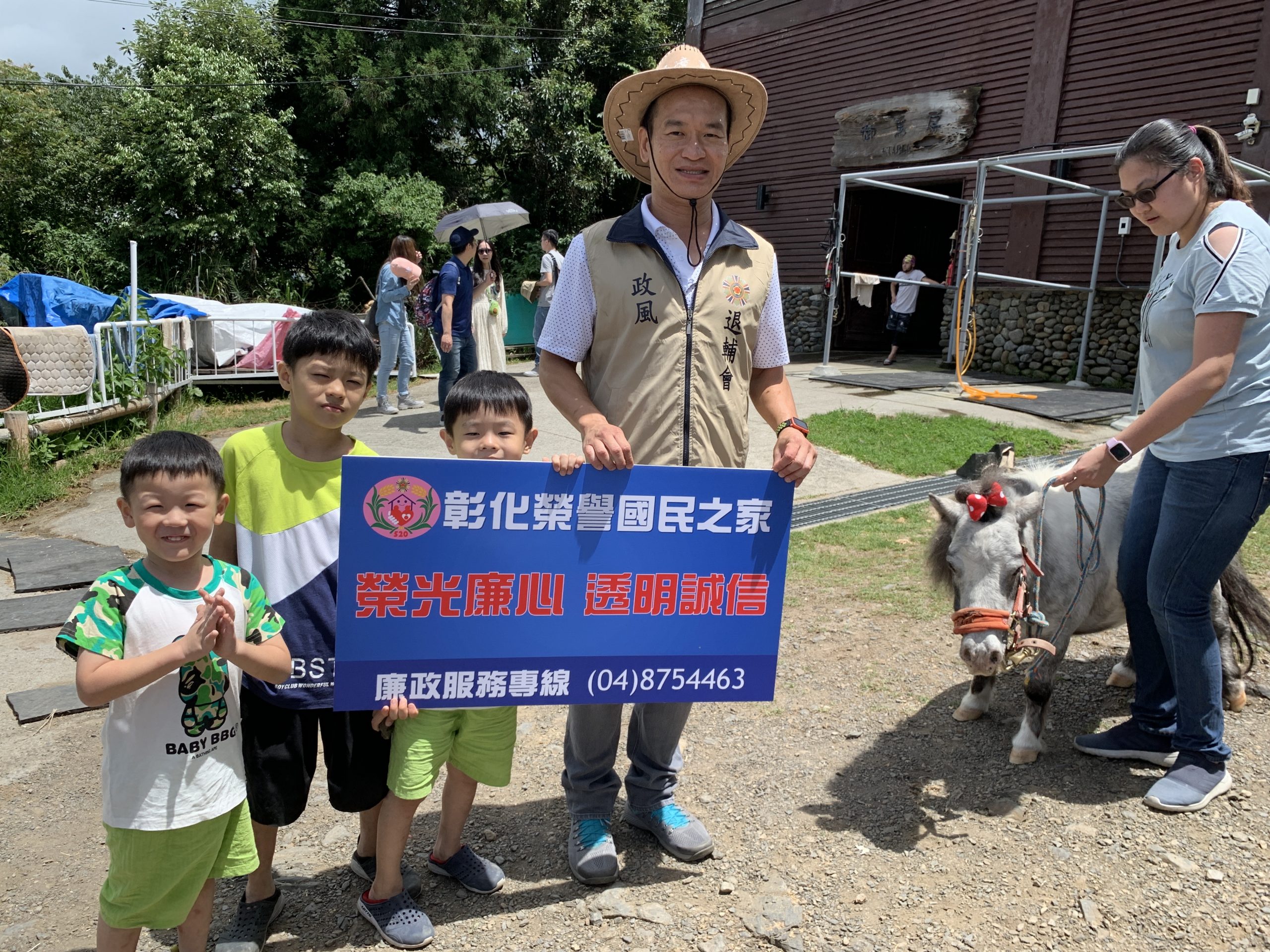 政風室主任劉昌元與學童手持宣導標語與來自荷蘭可供小朋友乘坐的超可愛迷你馬「嚕嚕米」合影